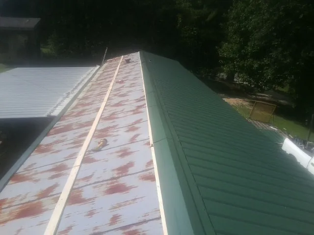 Old rusted panels beside newly installed green metal roofing — Wind Damage Roof Repair by Roofing Brothers in Dundee