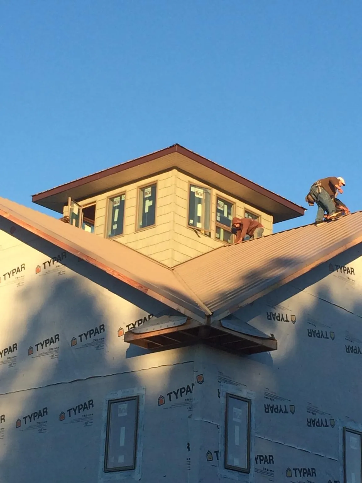 Roofers working around a rooftop cupola on a new metal roof at sunset — Roof Waterproofing in Dundee by Roofing Brothers